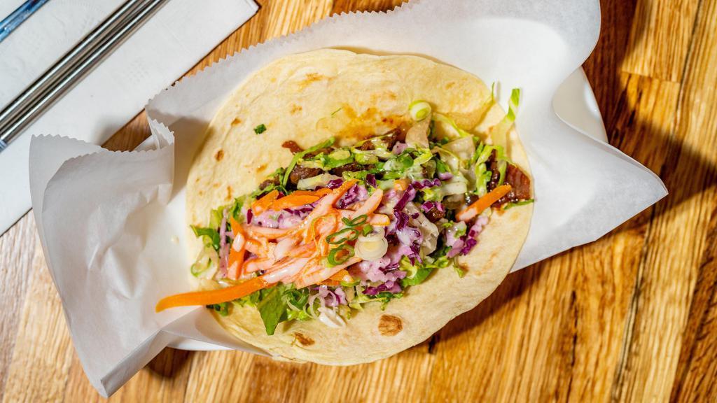 Bulgogi Taco · Premium rib-eye beef marinated in traditional bulgogi sauce with fresh ginger cabbage slaw, lettuce, and carrots topped with house-made kiwi sauce. Single serving.