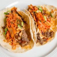 Austin Cho Tacos · Smoked Brisket, Fatcho BBQ  Sauce, Kimchi, Remoulade, Scallions on 2 Flour Tortillas.