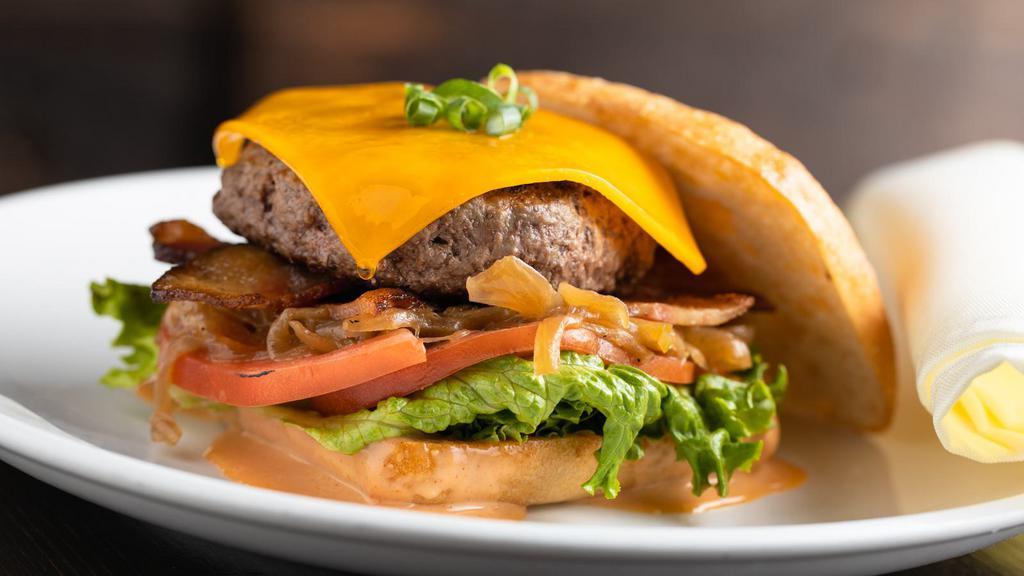 Deluxe Burger · Bacon, tomato, cheddar cheese, lettuce, and house sauce. Served on Brioche bread with mixed greens with the choice of soup, salad or hand-cut fries.