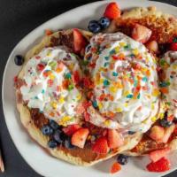 -Bedrock Pancakes · Fruity Pebbles pancakes topped with berries, berry maple syrup and whipped cream.