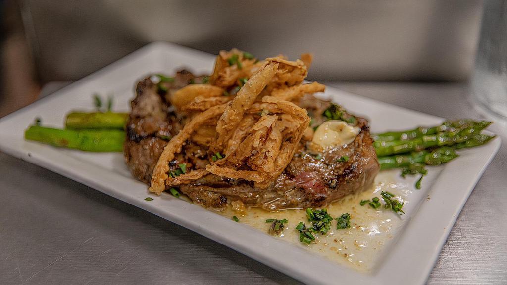Prime New York · Marinated  New York strip, served with garlic Truffle butter, and a heaping amount of fried onions and seasonal vegetables