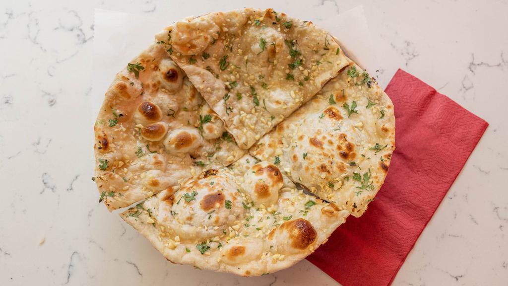 Garlic Naan · Tandoori oven baked bread topped with garlic and herbs.