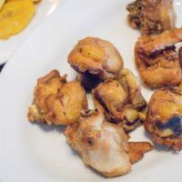 Chicharron De Pollo Con Tostones · Fried chicken pieces with fried plantains.