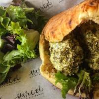 Herbed Falafel Sandwich · Our green falafel with tahini sauce, romaine hearts, and red cabbage inside of a pita.