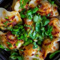 Pork Yumplings · Pan-fried pork & garlic chive dumplings. Topped w/ homemade chili oil & sesame seeds and gar...
