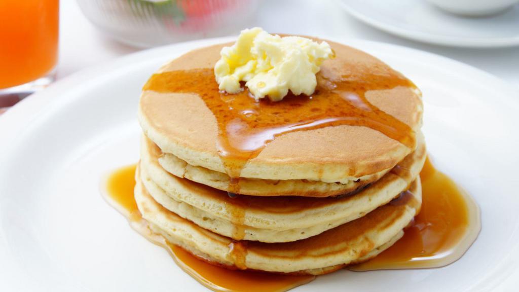 Buttermilk Pancakes · Fluffy pancake  stack with butter and syrup.