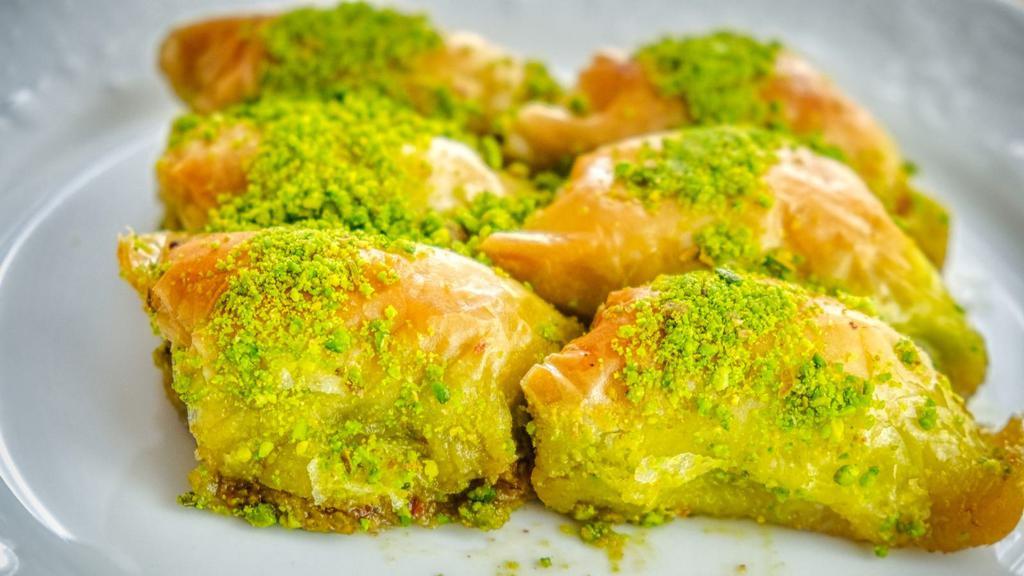 Baklawa · Flaky layered filo pastry, filled with finely chopped walnuts, drenched with honey and topped with crushed pistachios.