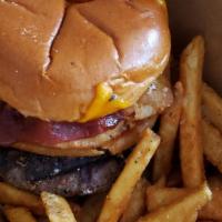 Rodeo Burger · 10 oz Burger Topped with sharp cheddar, onion rings, and covered in a barbecue sauce on a to...