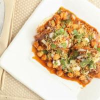 Samosa Chat · Crushed crunchy samosa topped with chickpeas, sweet and tangy chutneys, onion, coriander, an...