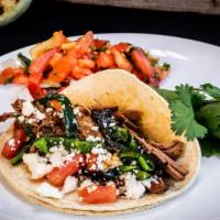 Machaca Taco · Braised shredded beef with poblanos, tomato, and queso fresco.
