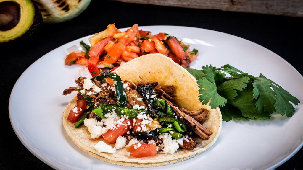 Machaca Taco · Braised shredded beef with poblanos, tomato, and queso fresco.