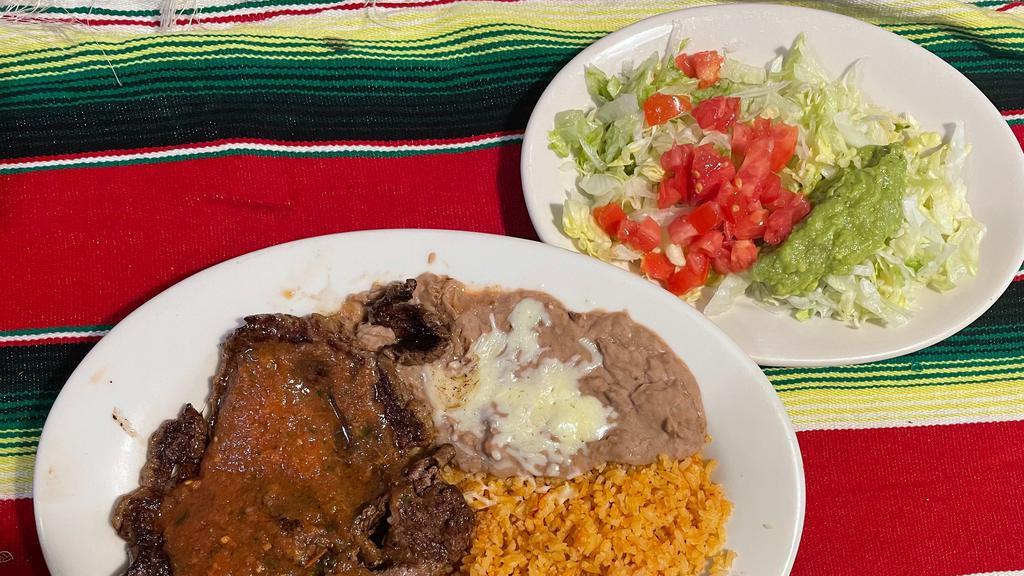 Steak Ranchero · Rb-eye steak topped with green and yellow squash, cheese sauce, served with cuacamole salad, rice, beans and 3 tortillas
