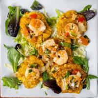 Camarones Con Tostones · Sautéed shrimp with garlic sauce over fried green plantains.