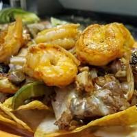 Nachos Texanos · Incluye bistec, chorizo, lechuga, crema, queso, frijoles,  tomates, y jalapeños (includes st...