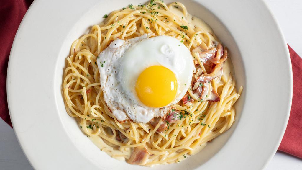 Linguine Carbonara · Linguine tossed with smoky bacon and onions in a cream sauce, topped with a sunny side up egg.