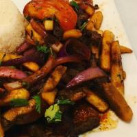 Lomo Saltado · Sliced beef stir fried with red onions, tomatoes, soy sauce, vinegar and cilantro mixed with...