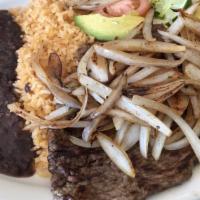 Bistec Encebollado · Grilled steak topped with sautéed onions served with a side salad, rice, and beans.