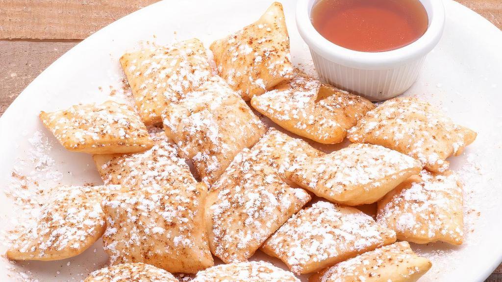 Sopapillas · Puffed Mexican pastries dusted with cinnamon and powdered sugar and served with a side of honey for dipping.
