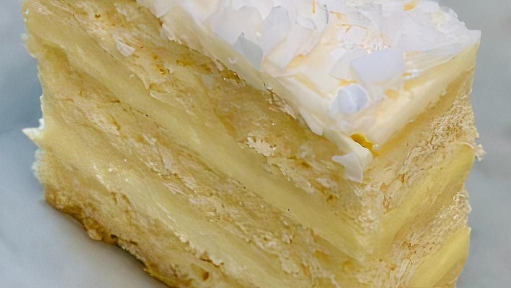 Coconut Cake · Moist vanilla cake made with fresh grated coconut, layered with crème fraiche pastry cream, coated with butter cream and toasted coconut flakes