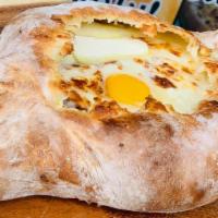 Adjaruli Khachapuri · Vegetarian. Adjaruli khachapuri is a boat-shaped bread stuffed with melted cheese ,  topped ...