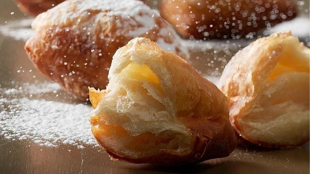 Croissant Beignet · Our Croissant Beignet is a flaky spin on the traditional beignet. As a feature in homestyle Creole cooking, beignets are typically made from deep-fried choux pastry. By utilizing croissant dough instead, our Croissant Beignet maintains a flaky texture and a soft, richly flavored interior. Dusted with confectioner’s sugar