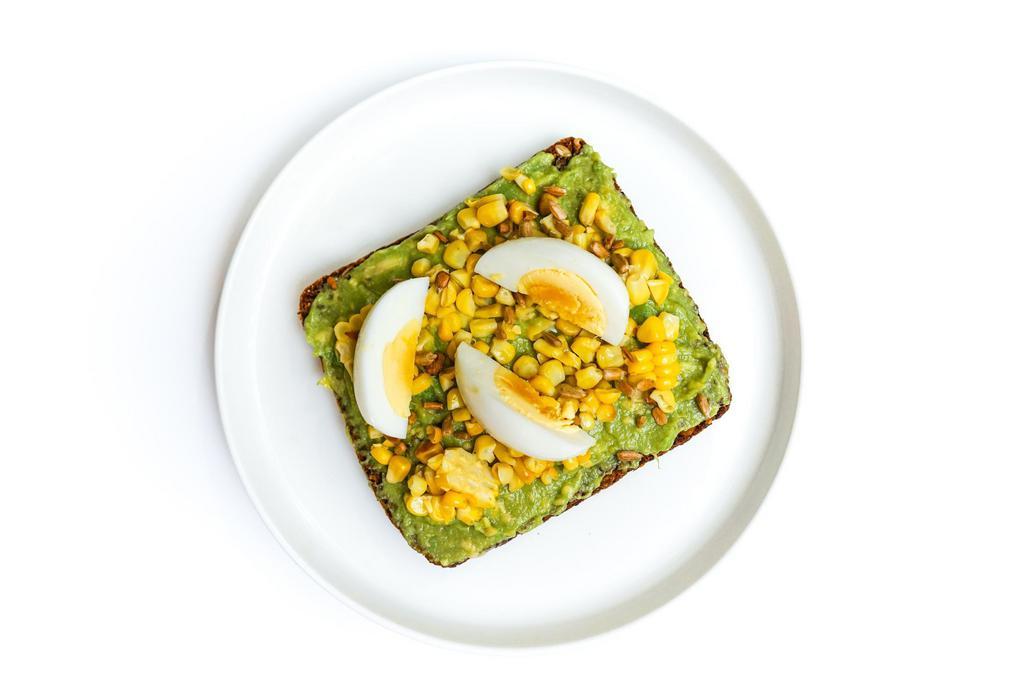 Avocado · Just-smashed avocado, grilled corn, and a sliced hard boiled egg with sunflower seeds on top