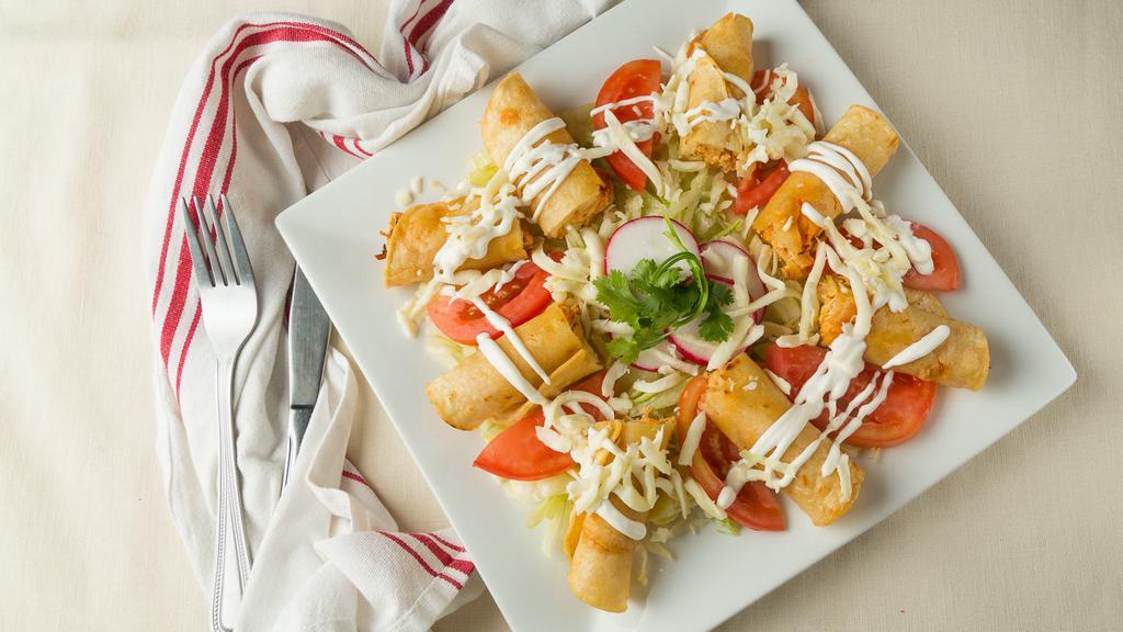 Tacos Dorados · Fried chicken tacos topped with sour cream, lettuce, onions, and queso fresco.