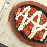 Iskander Kebab · Beef and lamb shawarma topped on bread and covered by a layer of yogurt sauce and red sauce.
