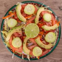 Ensalada Verde · Chopped lettuce, tomatoes, avocado, cucumber, grated carrots, sliced red onions & lime on th...