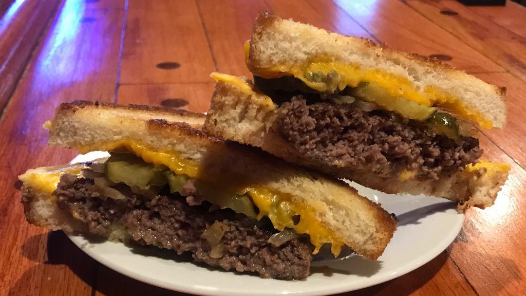 Toli'S Grilled Cheese Burger · Fresh ground beef burger, grilled onions & pickles. Layered with American and Cheddar cheese in between two slices of grilled Texas toast.  The ultimate grilled cheese.