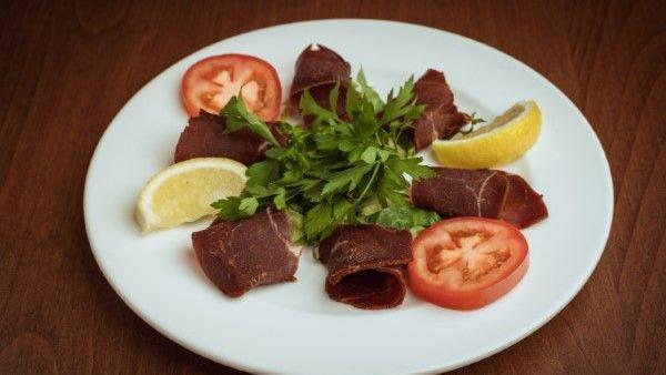 Pastrami Plate · Delicious Turkish pastrami served with hummus, shaved cheese, tomato slices, and arugula leaves.