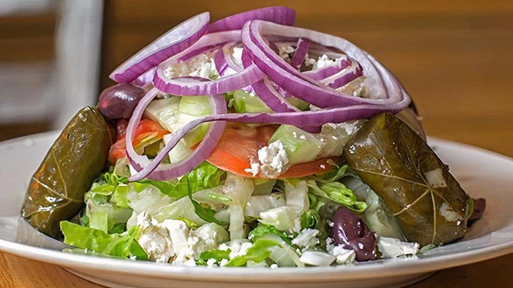 Greek Salad · Romaine, tomatoes, cucumbers and red onions, topped with feta, Kalamata olives, meatless grape leaves and red wine vinaigrette.