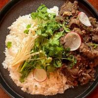 Truffle Bulgogi Rice / 트러플불고기덮밥 · Thinly sliced marinated ribeye over rice with cilantro and truffle on a sizzling stone pan.