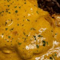 Chuletas De Puerco · Abodo seasoned pork chops in a mustard cream sauce, with a touch of tomato and served with c...