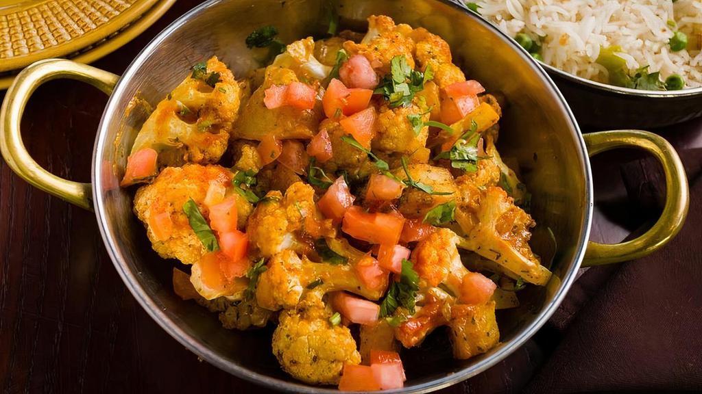Tawa Aloo Gobi · Cauliflower and potatoes cooked with fenugreek and a blend of Indian spices in a flat cast iron pan
