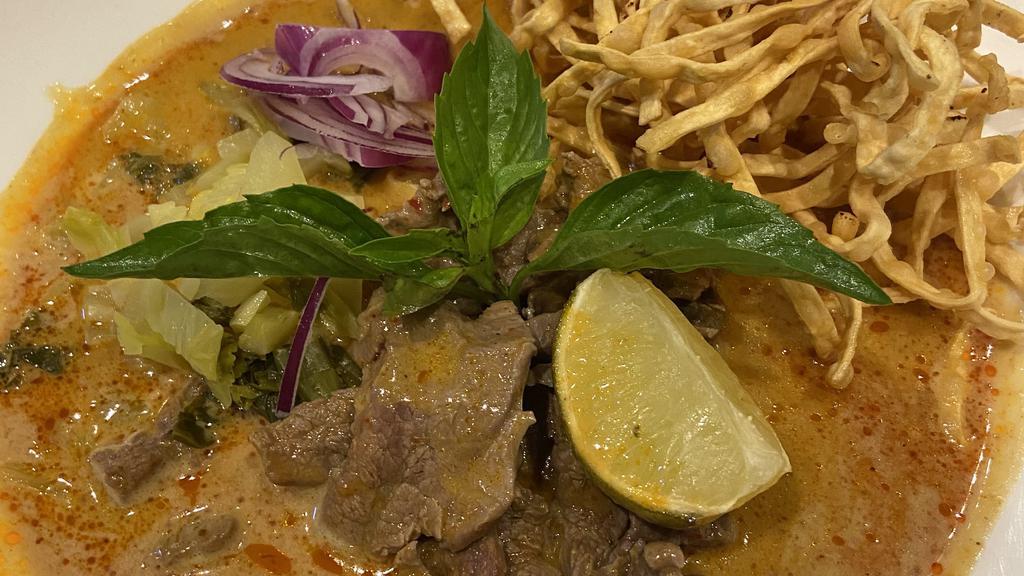 Khao Soi Beef · Northern style special curry served with egg noodle, red onions, pickled mustard, fried shallots and topped with crispy noodles.