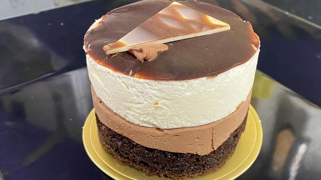 Triple Layer Mousse · A layer of rich chocolate cake, dark chocolate mousse, and white mousse, topped with chocolate ganache and a chocolate decoration