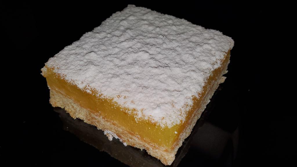 Lemon Square · Tart lemon squares topped with fine powdered sugar on a soft flaky crust
