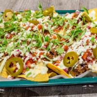 Nachos · Tortilla chips with choice of meat layered with cheese sauce, avocado crema, black beans, pi...