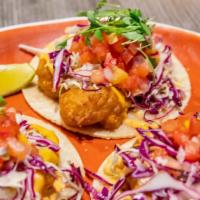 Shrimp Tacos · Our signature fried shrimp tacos topped with beer battered shrimps, kuhio cabbage slaw, mang...