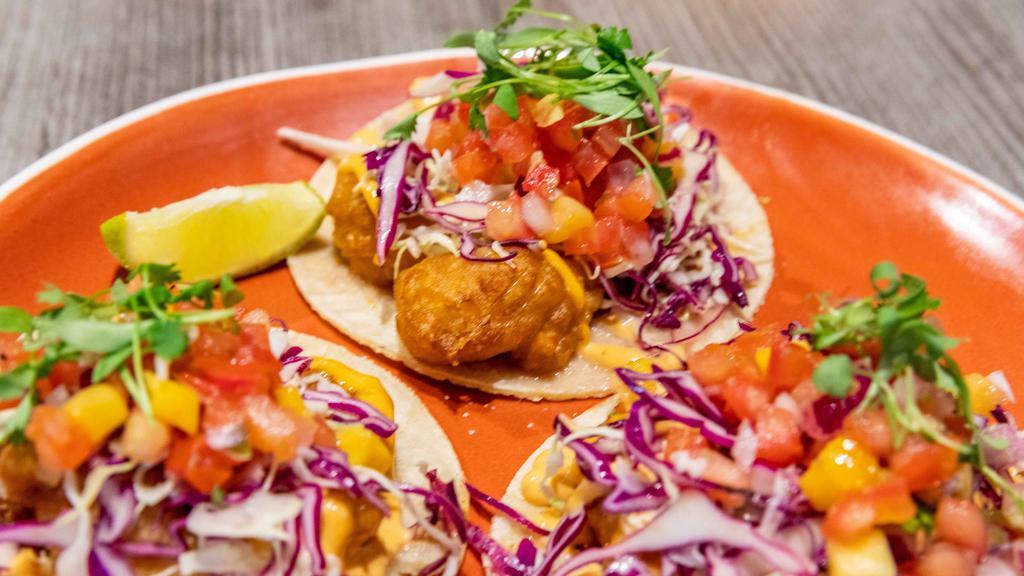 Shrimp Tacos · Our signature fried shrimp tacos topped with beer battered shrimps, kuhio cabbage slaw, mango salsa, chipotle mayo, and lime