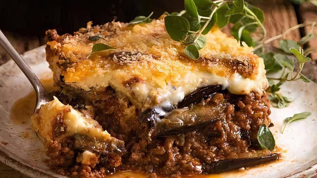 Mousaka · Baked layers of eggplant and ground beef on a layer of potato, topped with béchamel sauce. Served with side Greek salad.