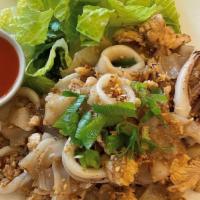 Guay Tiew Kua · Wok-fried flat noodles with eggs on a bed of romaine lettuce served with a side of Sriracha ...