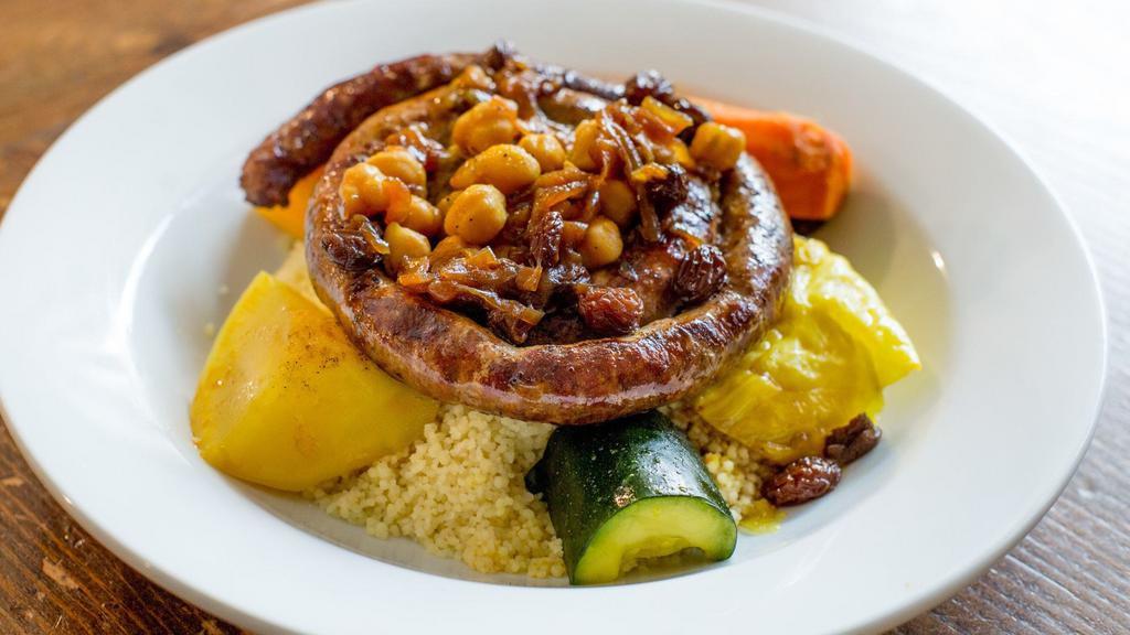 Merguez Couscous · house-made spicy lamb & beef sausage, braised butternut squash, carrots, zucchini, celery, turnips, served over a bed of fluffy couscous, topped with chickpeas, raisins, & caramelized onions