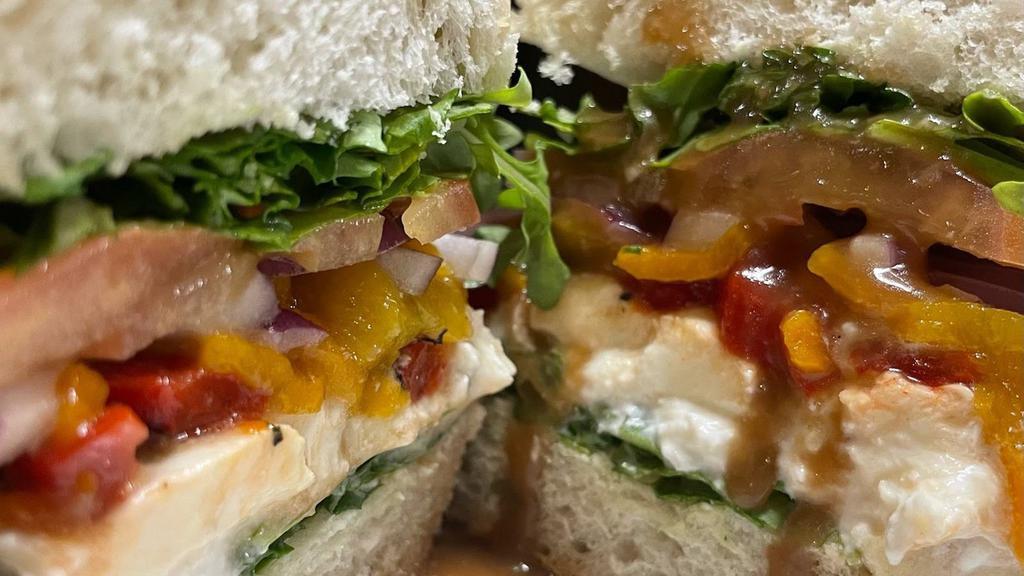 Burrata Sandwich · Black truffle burrata sliced and served on a baguette with house made maple balsamic vinaigrette, roasted red and yellow peppers, red onion, arugula and tomatoes. Served with your choice of fries or a salad.