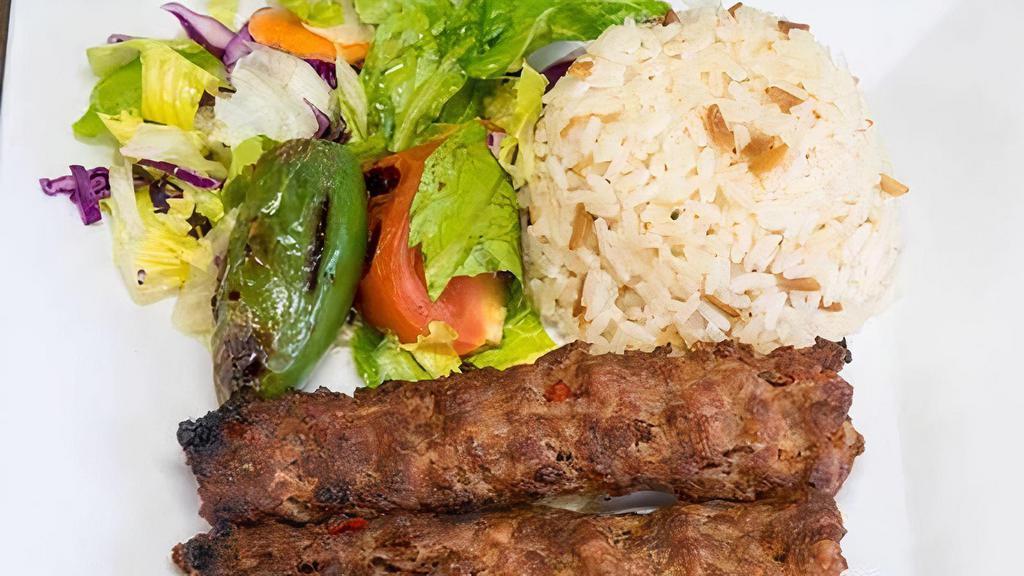 Adana Kebab · Ground lamb seasoned with spice and red peppers, gently spiced with paprika and grilled on skewers. Served with rice and salad.