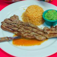 Bistec Al Carbon · Grilled shell steak, side of guacamole, served with rice and beans.