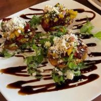 Chorizo Kisses · On crispy plantains with guacamole and lightly drizzled with tropical mango sauce