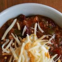 Betty'S Chili · Seasoned chili served in a bowl topped with cheddar cheese and onion. Served with tortilla c...