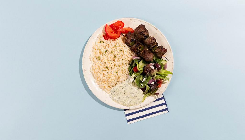 Beef Soulvaki Rice Platter · Grilled beef skewers served with rice, salad, pita bread, and tzatziki.